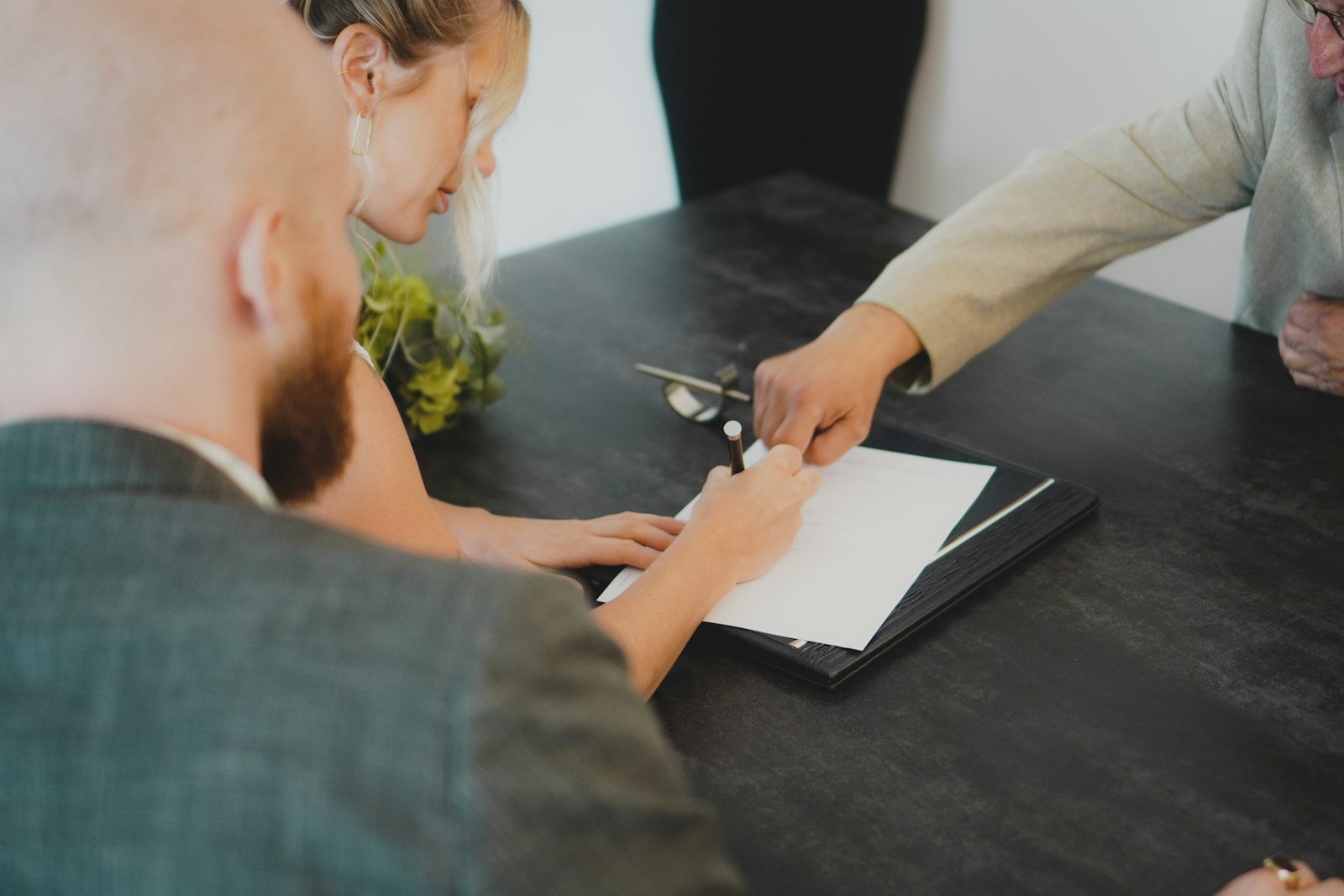 A couple signing papers at a desk, with the keys on the table