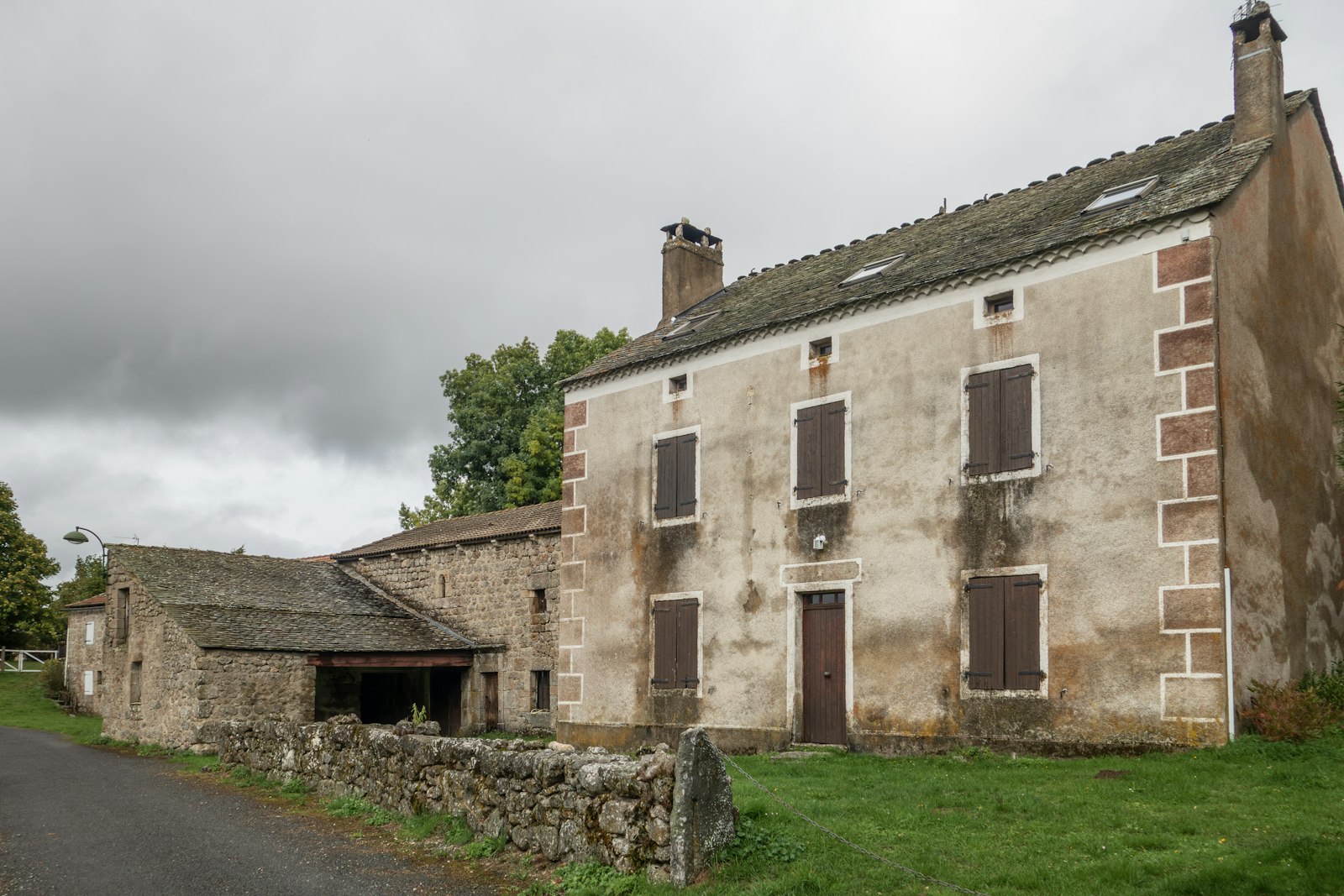Old stone farmhouse with a barn beside a country lane in the south of France